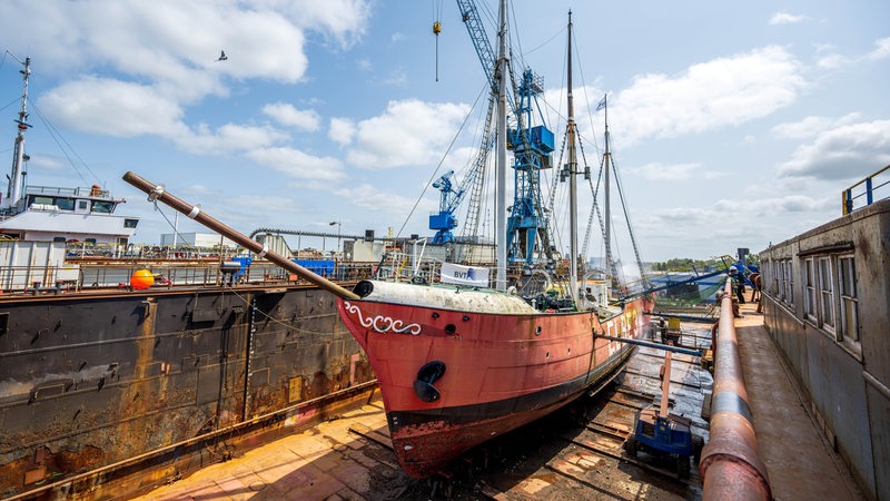 Ein rotes Schiff liegt auf dem Trockenen in einem Dock.