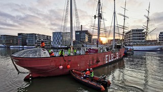 Die Elbe 3 wird an der Bremerhavener Skyline entlanggeschleppt.