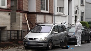 Zwei Spurensucher der Polizei stehen vor einem Hauseingang.