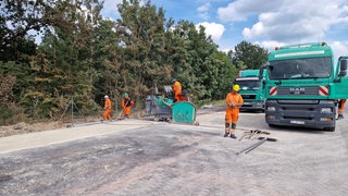 Bauarbeiter arbeiten an der Fahrbahn einer Autobahn.