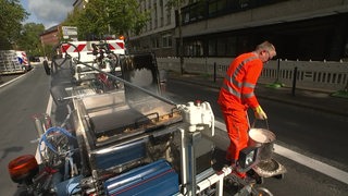 Ein Bauarbeiter markiert einen neuen Radweg auf der Martinistraße in Bremen.