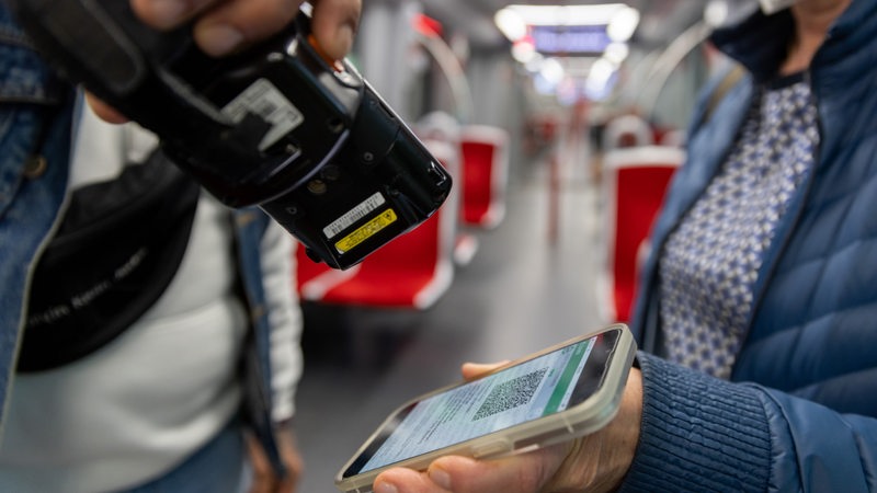 Ein Fahrkartenkontrolleur kontrolliert mit einem elektronischen Lesegerät in der U-Bahn Gäste.