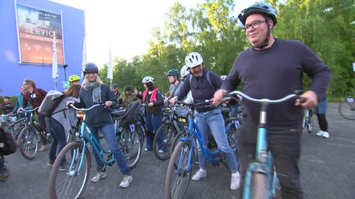 Mehrere Radfahrende mit ihren Fahrrädern, kurz vor der Abfahrt.