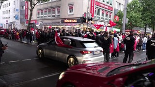 Türkei-Fans schwenken Fahen aus Autos und auf dem Gehweg.