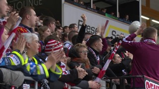 Fans eines Sportvereins feuern ihr Team von einer Tribüne aus an