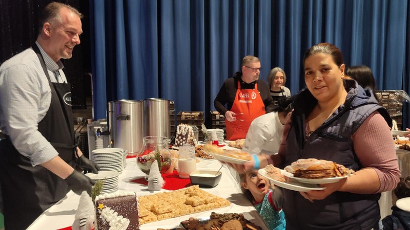 Mehrere Personen stehen vor und hinter einem Tisch mit Kuchen.