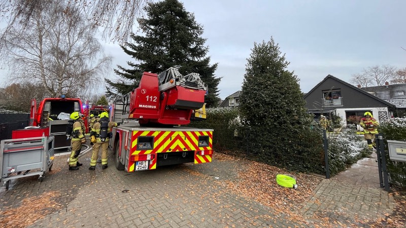 Ein Feuerwehrfahrzeug und Feuerwehrkräfte vor dem betroffenen Haus.