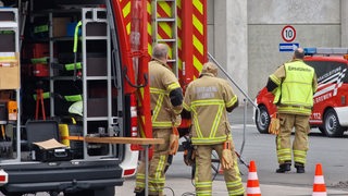 Feuerwehrleute stehen vor einem Gebäude.