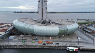 Zwei Feuerwehrautos und ein Polizeiauto stehen vor dem Klimahaus in Bremerhaven.