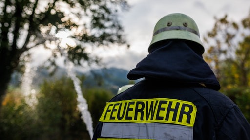 Zwei Feuerwehrleute geben während einer Einsatzübung einer Freiwilligen Feuerwehr Wasser aus einem Schlauch ab.