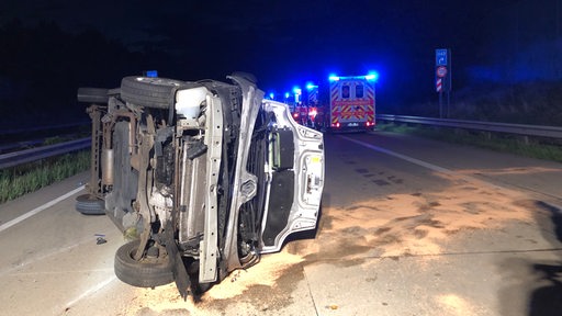 Nach einem Unfall liegt ein Kleinbus auf einer Autobahn auf der Seite.