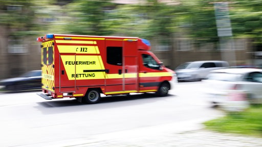 Ein Rettungswagen fährt in hoher Geschwindigkeit eine Straße entlang.