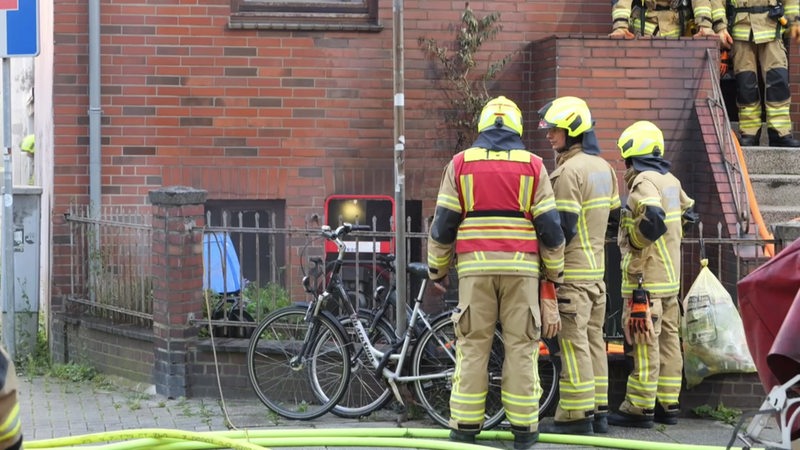 Ein paar Feuerwehrkräfte vor einem Wohnhaus.