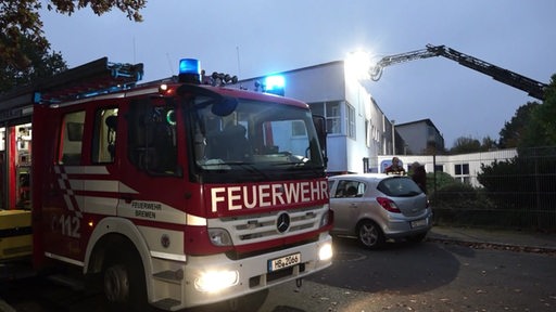 Ein Feuerwehrfahrzeug mit Blaulicht vor einem Industriegebäude