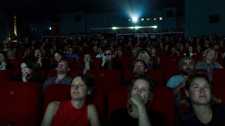 Menschen sitzen in einem dunklen Kinosaal