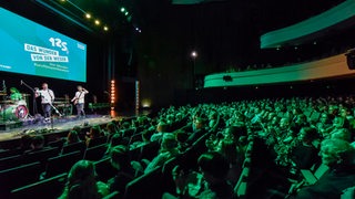 Volles Auditorium im Bremer Theater am Goetheplatz, auf der Bühne Sprecher und Filmfest-Leinwand