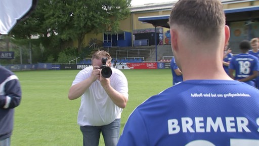 Ein Fotograf fotografiert einen Fußballspieler.