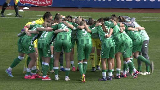 Werders Frauen der 1. Bundesliga bilden auf dem Rasenfeld einen Kreis.