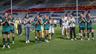 Werders Fußballerinnen stehen nach dem verlorenen Saisonfinale in Freiburg enttäuscht auf dem Spielfeld und applaudieren den mitgereisten Fans.
