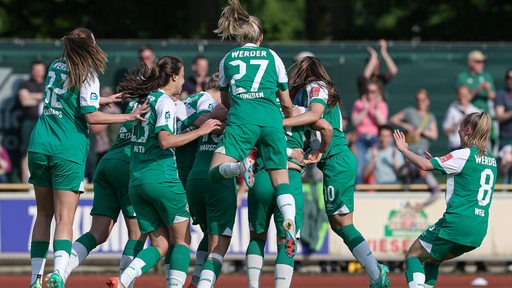 Werders Fußballerinnen kommen zu einer Jubeltraube nach einem Tor auf dem Feld zusammen.