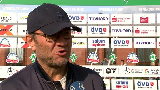 Werder-Trainer Thomas Horsch steht mit einer dunklen Kappe vor einer Werbewand beim Interview nach dem Spiel gegen Potsdam.