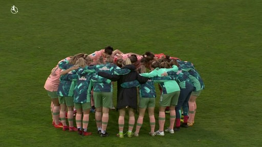 Werders Bundesligaspielerinnen beim aufwärmen in einem Kreis auf dem Fußballfeld. 