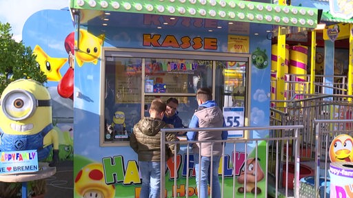 Zwei Jungs stehen an der Kasse eines Freimarkt-Karussells.