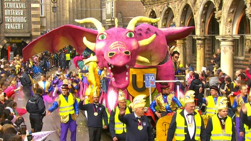 Eine Menschenmenge mit eine großen Drachenfigur vor dem Bremer Rathaus