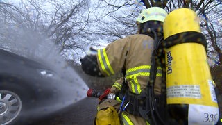 Freiwillige Feuerwehrleute löschen bei einer Übung ein Auto