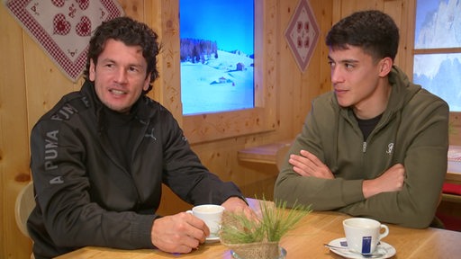 Die Werder Fußballspieler Nelson Valdez und Julian Malatini sitzen bei einem Kaffee in einer Almhütte.