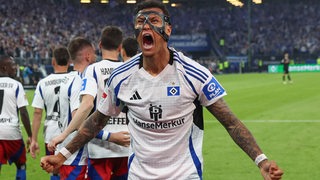 Der Fußball-Profi des Hamburger SV Davie Selke trägt eine schwarze Maske im Gesicht und schreit mit martialischer Geste seinen Torjubel hinaus.