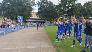 Fußball-Spieler des Bremer SV feiern den Sieg vor der Fangerade am Panzenbergstadion.