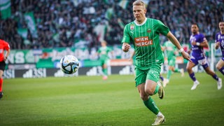 Marco Grüll rennt im Trikot von Rapid Wien im Spiel gegen Austria Wien dem Ball hinterher.