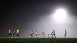 Mehrere Fußballer trainieren im Flutlicht.