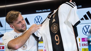 DFB-Stürmer Niclas Füllkrug hält sein Trikot in die Höhe.