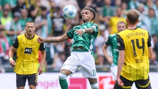 Werder-Stürmer Justin Njinmah bei der Ballannahme mit der Brust im Duell mit Dortmunder Gegenspielern.