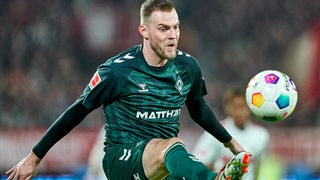 Werder-Stürmer Marvin Ducksch fukussiert sich im Spiel auf den Ball in der Luft vor ihm, den er treffen will.