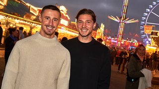 Die Werder-Spieler Marco Friedl und Niklas Stark posieren auf der Freimarkt lächelnd vor der Kamera.