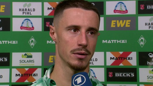 Werder-Kapitän Marco Friedl steht vor einer Werbewand bei einem Interview nach der Niederlage gegen Freiburg.