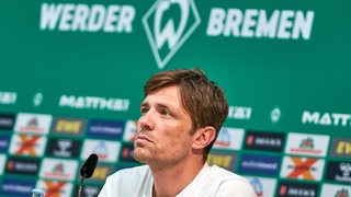 Werders Sportchef Clemens Fritz sitzt nachdenklich bei einer Pressekonferenz.