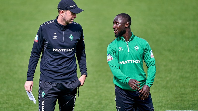 Werder-Trainer Ole Werner spricht am Rande des Trainings mit Spieler Naby Keita.