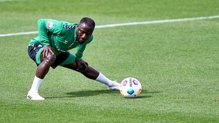 Werder-Neuzugang Naby Keita dehnt sein linken Bein am Rande des Trainings.