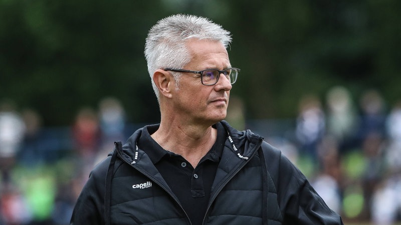 Ralf Heskamp steht auf einem Fußballplatz und schaut zur Seite.