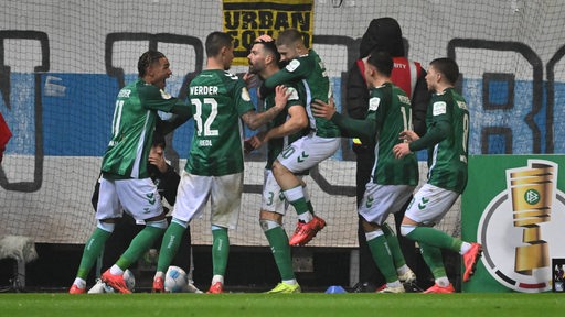 Werder-Spieler umarmen Torschütze Anthony Jung im Pokalspiel gegen Darmstadt.