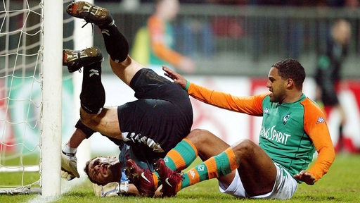 Werder-Spieler Ailton rutscht im Pokal-Halbfinale gegen Lübeck vor den Torwart, der einen Purzelbaum beim Abwehrversuch schlägt.