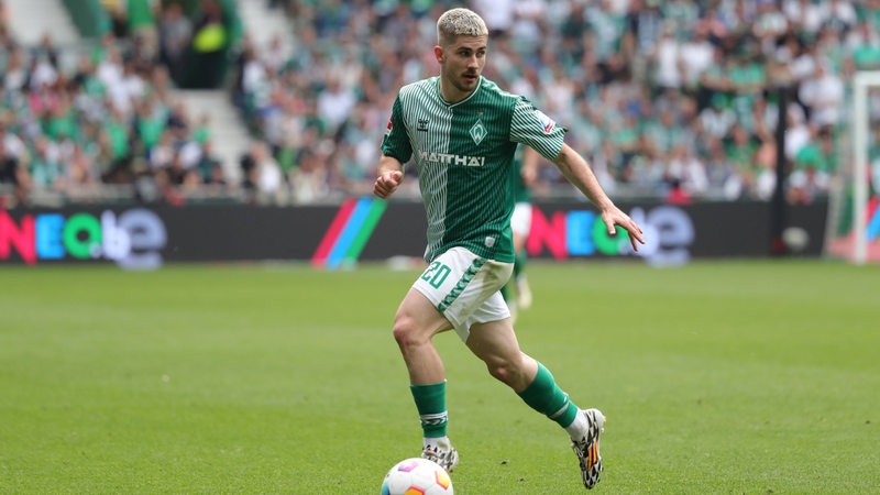 Werder Bremens Romano Schmid steht auf dem Platz und führt den Ball am Fuß.