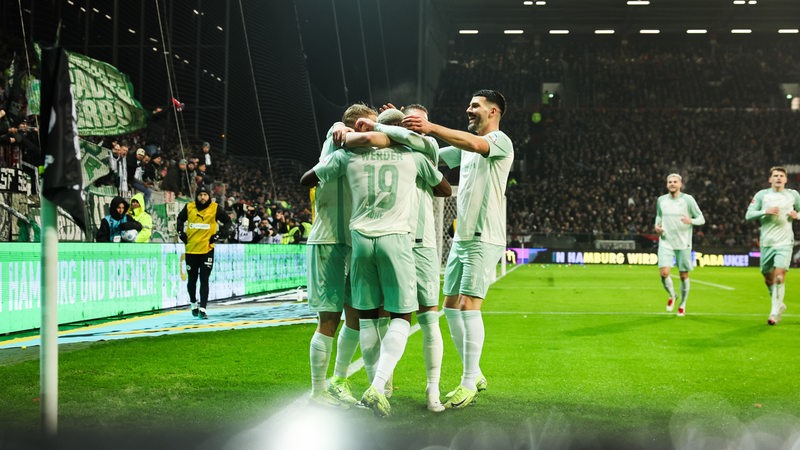 Werder-Spieler umarmen an der Eckfahne des Millerntor-Stadions ihren Torschützen Derrick Köhn.