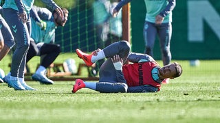 Werder-Kapitän Marco Friedl liegt im Training mit Schmerzen am Boden und hält sich den rechten Knöchel.