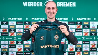 Ole Werner hält das neue Werder-Trikot in der Hand