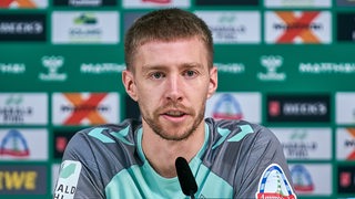 Mitchell Weiser sitzt bei einer Pressekonferenz des SV Werder Bremen.